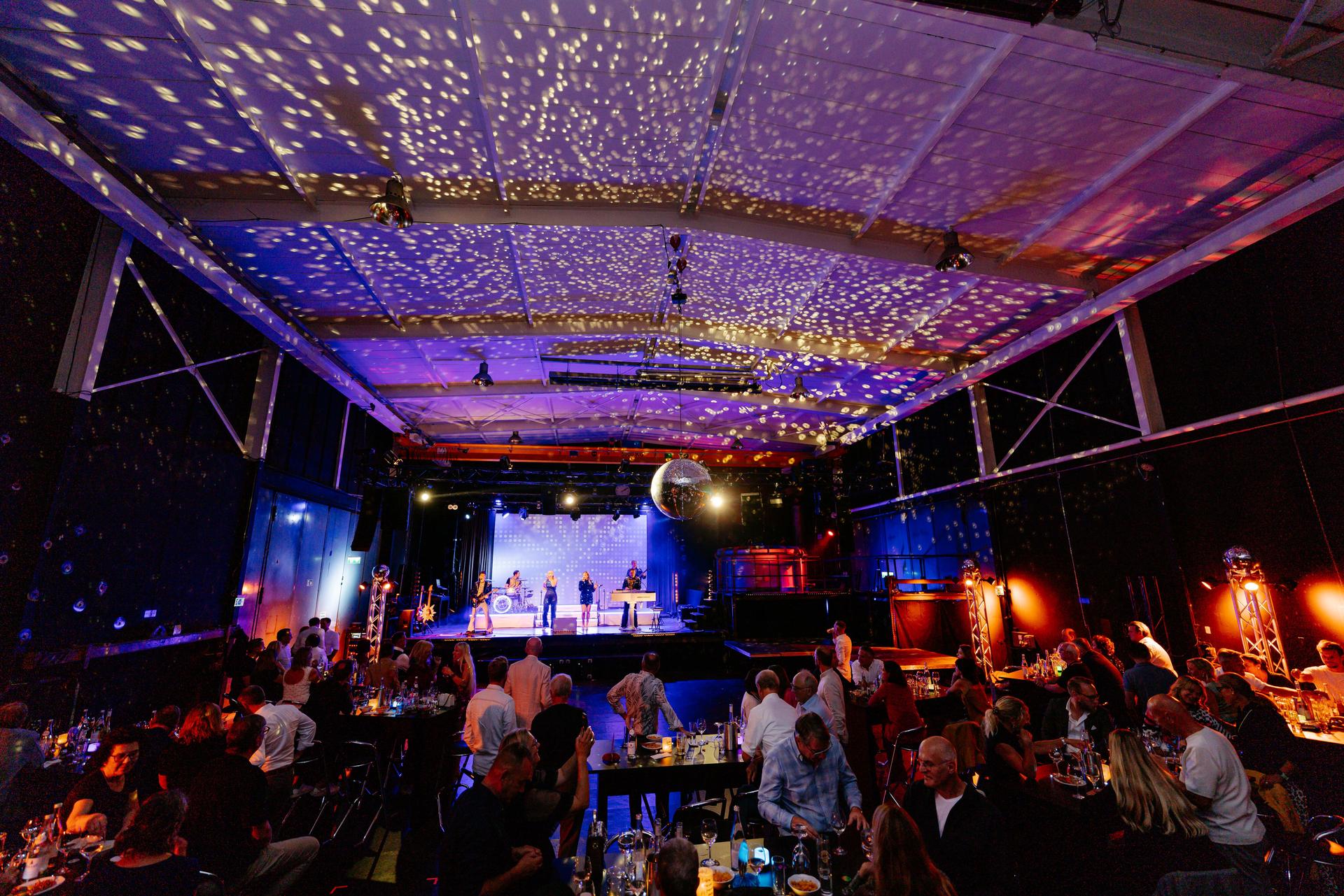 Eventhalle mit Lichtpunkten an der Decke, Band auf der Bühne